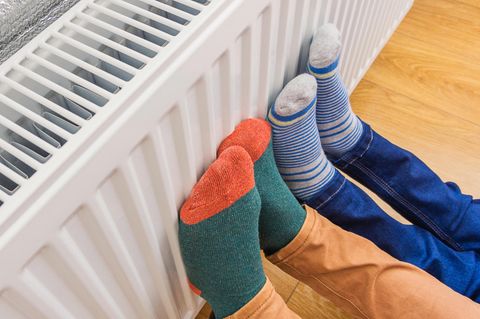 Energiekosten sparen im Kinderzimmer: Mama und Kind wärmen Füße an Heizung