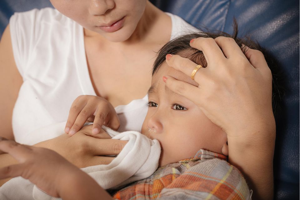 Magen-Darm-Alarm: Eine Frau umsorgt ihr krankes Kind auf dem Sofa