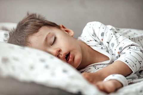 Kopfkissen-Test: Junge im Pyjama schläft bequem auf einem Kopfkissen.