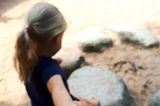 Bereute Mutterschaft: Evelines Tochter hält eine Hand und steht vor einem Steinkreis