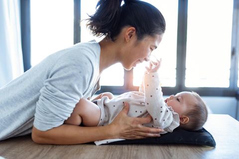 Körperbewusstsein fördern: eine Frau wickelt ihr Baby