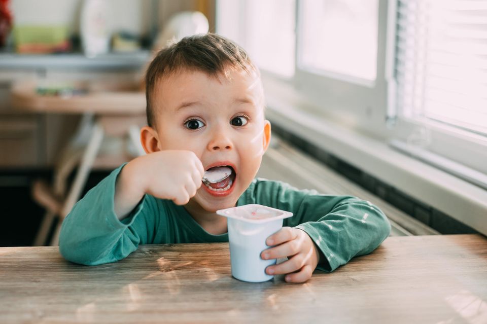 8 ungesunde Kinderlebensmittel: Junge isst einen Joghurt
