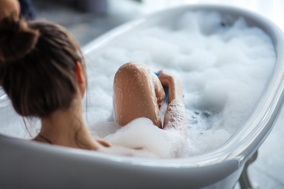 Erkältungsbad in Schwangerschaft: Frau liegt in der Badewanne und entspannt sich