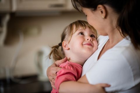 Familienkolumne: Eine Mutter hält liebevoll ihre kleine Tochter im Arm