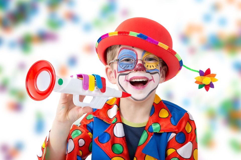 Kind ist als Clown verkleidet und freut sich darüber