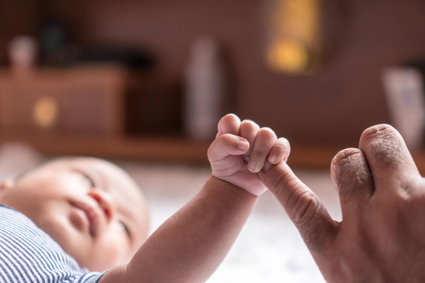 Baby hat kalte Hände: Baby hält Finger eines Erwachsenen fest