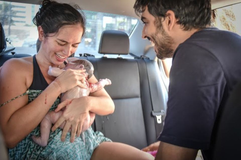 Geburt im Auto: Mutter und Vater mit Baby im Fahrzeug