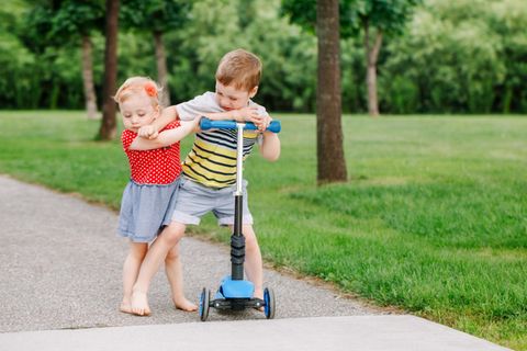 Teilen lernen: Zwei Kinder streiten um einen Roller
