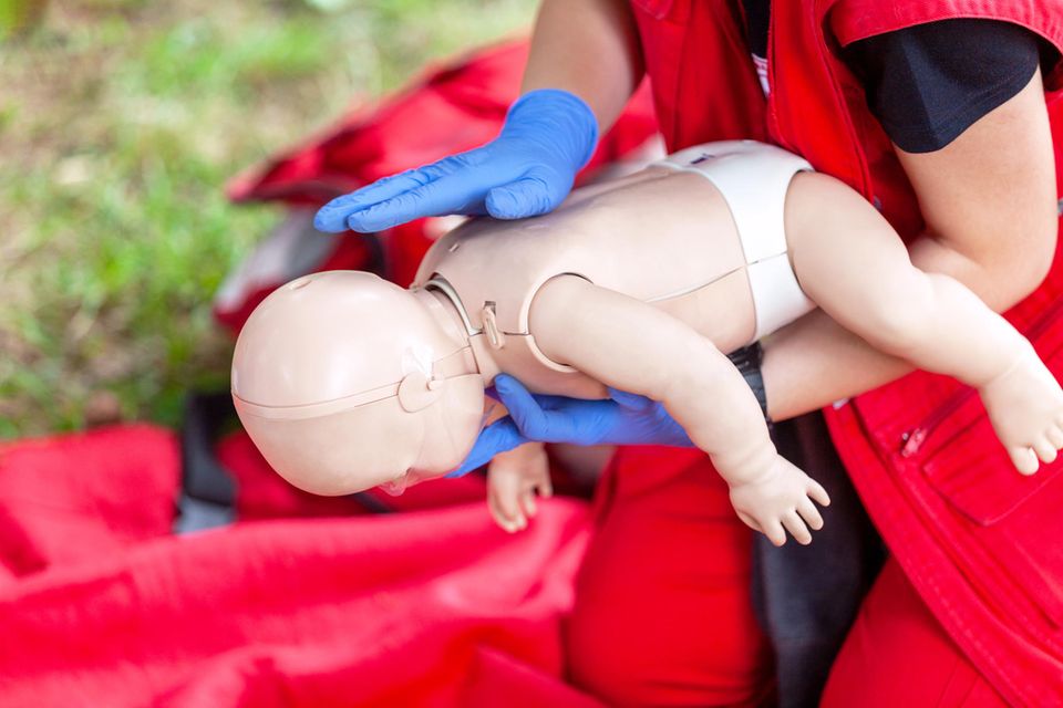 Erste Hilfe Kurse für Eltern: Ein Sanitäter mit einer Erste Hilfe Puppe eines Babys