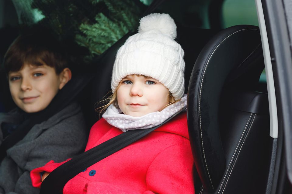 Mädchen und Junge sitzen angeschnallt in einem Auto