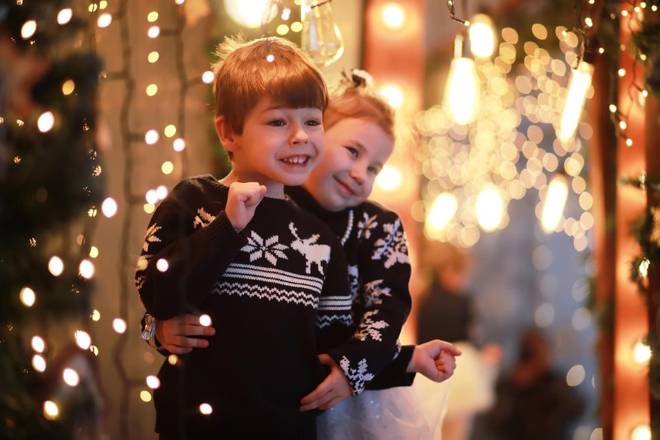Silvester-Spiele: Zwei fröhliche Kinder in festlich geschmücktem Zuhause