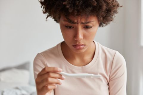 Junge Frau starrt besorgt auch einen Schwangerschaftstest