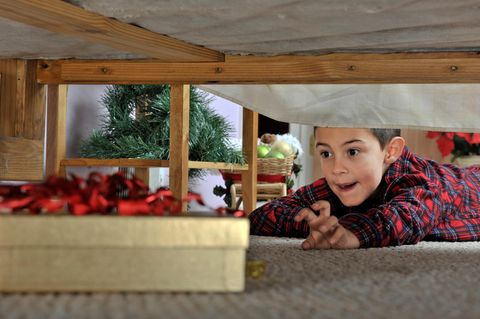 Wo lagert ihr Weihnachtsgeschenke bis zur Bescherung? Junge sucht unter dem Bett sein Geschenk