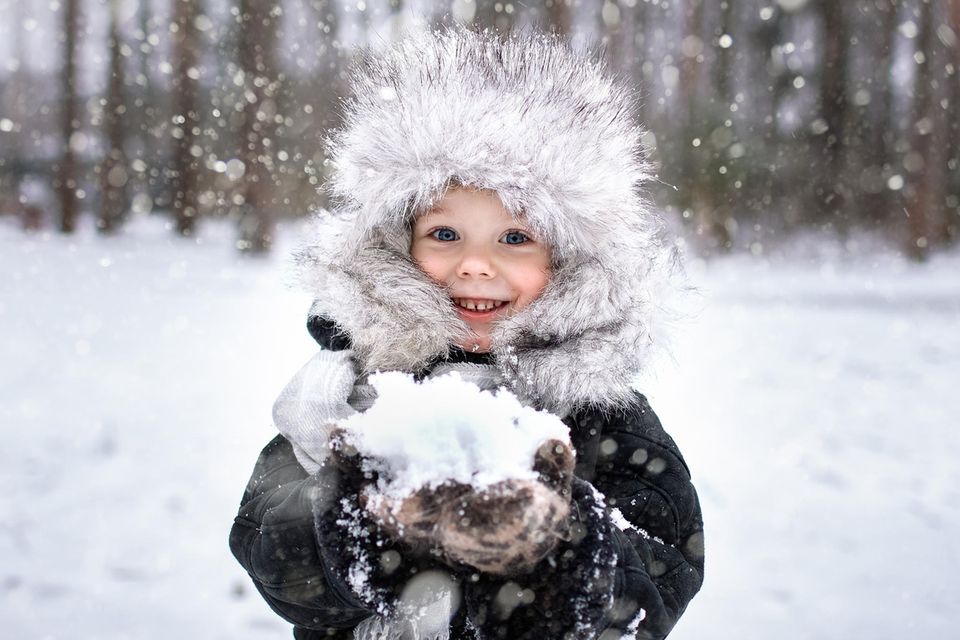 Ein Kind spielt fröhlich im Schnee