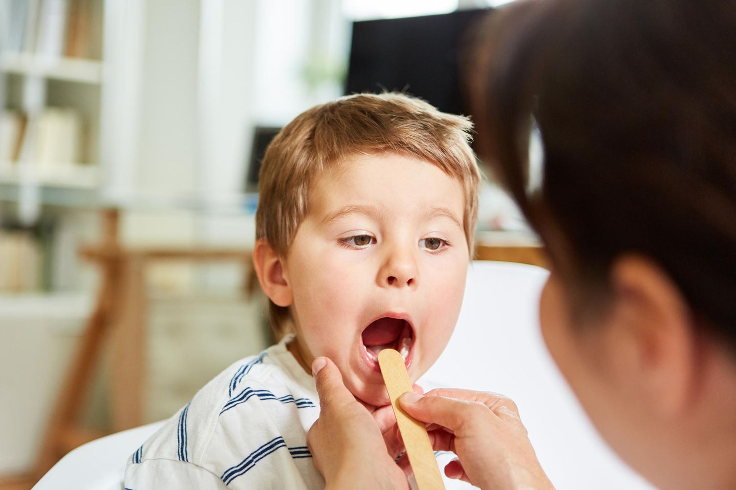 Kinderkrankheit Scharlach: Einem Kind wird mit einem Spatel in den Mund geschaut