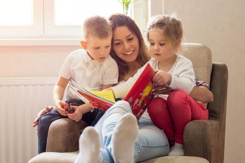 Kinderbücher ab 4 Jahren: Eine Mutter liest mit zwei 4-jährigen Kindern auf dem Schoß ein Buch