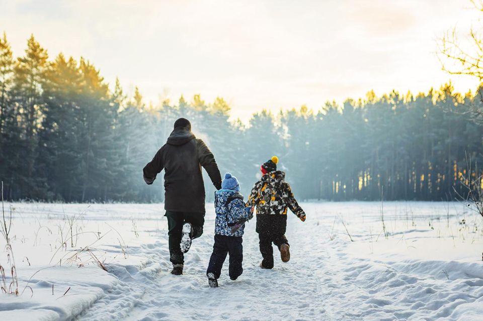 Hilfe, ich bin eine Stubenhocker-Mama: Kinder und erwachsene Person rennen durch ein schneebedecktes Feld