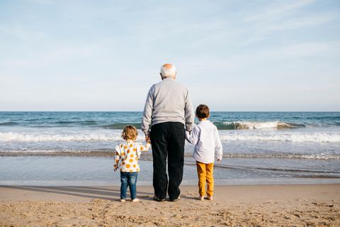 Erziehung damals und heute: Großvater steht mit seinen Enkeln am Meer