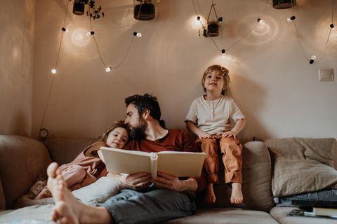 Gute Vorsätze für Eltern: Vater lies seinen Kindern eine Gutenachtgeschichte vor