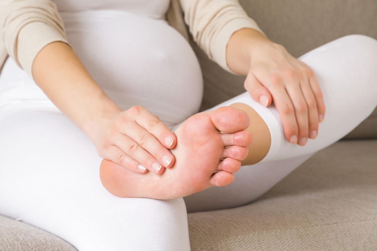 Wadenkrämpfe in der Schwangerschaft: Schwangere Frau hält sich Unterschenkel und Fuß