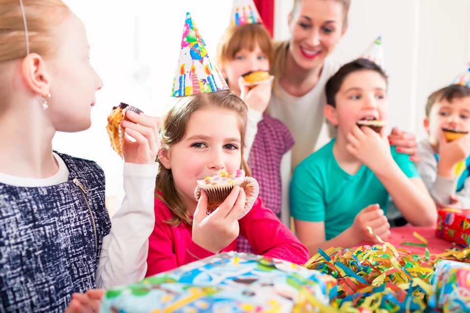 Kinder feiern einen Kindergeburtstag und essen Muffins