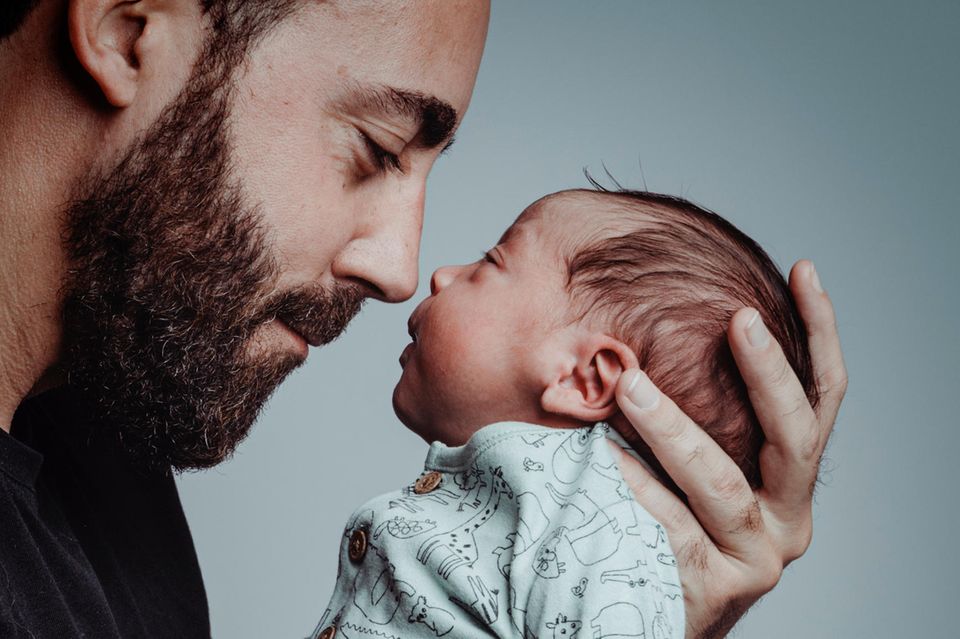 25 Wahrheiten über die Geburt: Vater schaut glücklich auf sein neugeborenes Kind