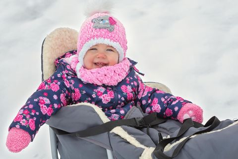 Babyschlitten-Test: Kleinkind sitzt in Babyschlitten mit Fußsack im Schnee