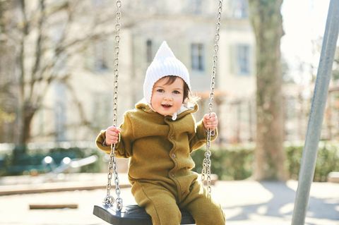 Kinder richtig anziehen: Kind sitzt auf einer Schaukel
