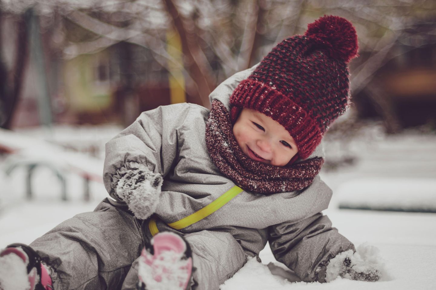 Overall für Babys: Kleines Kind im Winteranzug spielt zufrieden im Schnee