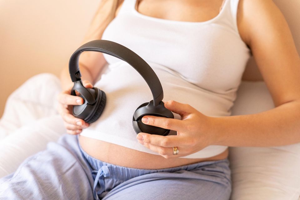 Gehörentwicklung: Eine schwangere Frau hält Kopfhörer auf ihren Bauch