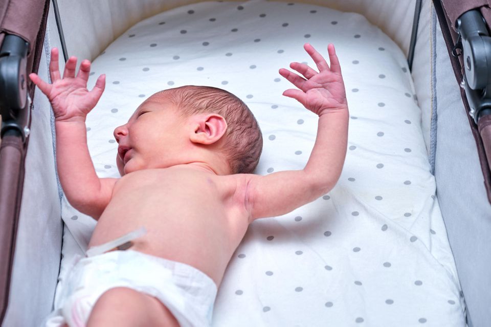 Moro Reflex: Neugeborenes streckt die Arme aus und spreizt die Finger