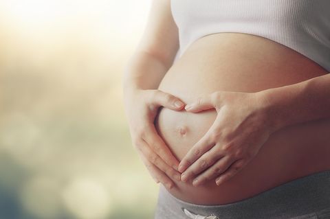 VBAC: Schwangere Person formt mit den Händen ein Herz vor ihrem Bauch