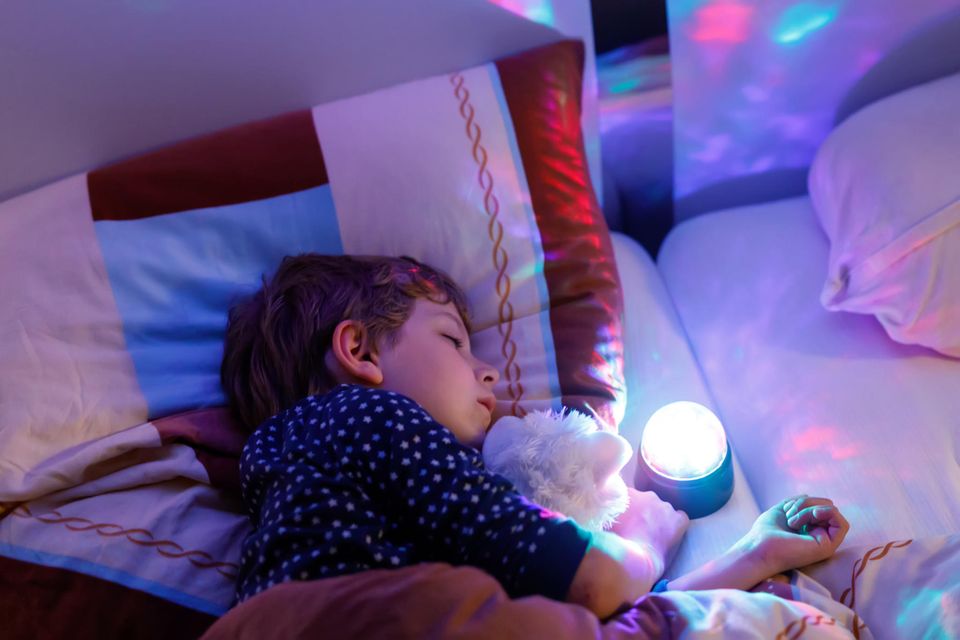 Nachtlichter für Kinder im Vergleich: Junge schläft bei sanftem Licht eines Nachtlichts