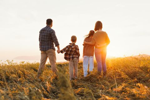 Flügge werden: Familie auf dem Feld, die zur Sonne guckt