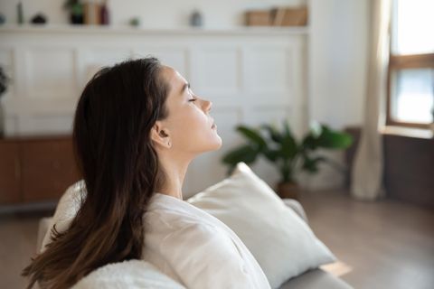 Fastenzeit: Frau sitzt mit geschlossenen Augen auf de Sofa
