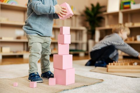 Pädagogische Ausrichtungen: Kind baut einen Turm aus rosafarbenen Bauklötzen