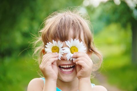 Mädchen hält sich Blüten vor die Augen