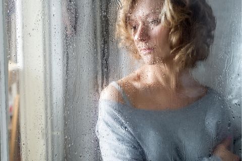 Frau sieht aus dem Fenster in den Regen