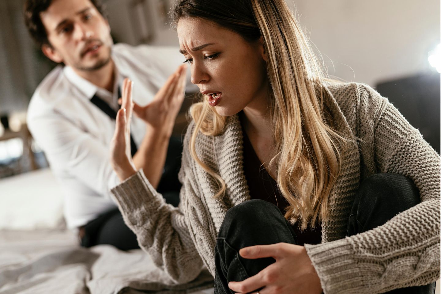 Frau hebt abwehrend die Hand gegen die Vorwürfe ihres Mannes