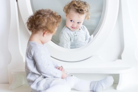 Sozialverhalten fördern: Ein kleines Mädchen schaut sich selbst im Spiegel an