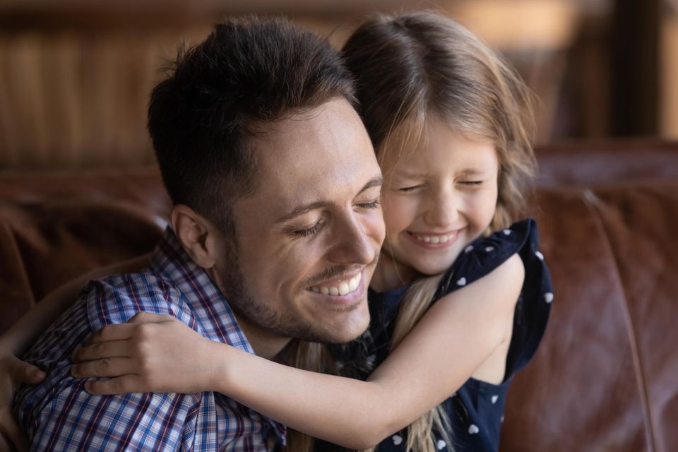 Ein kleines Mädchen umarmt fröhlich ihren Papa