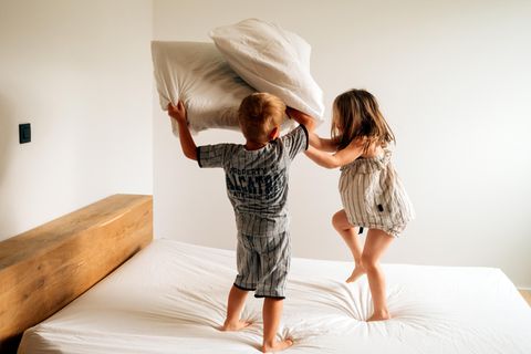Temperamentvolle Kinder: Zwei Kinder machen eine Kissenschlacht auf dem Bett