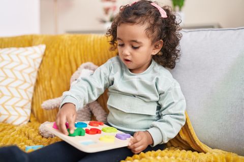 Konzentrationsübungen für Kinder: Kind sitzt auf einem Sofa und spielt konzentriert ein Spiel