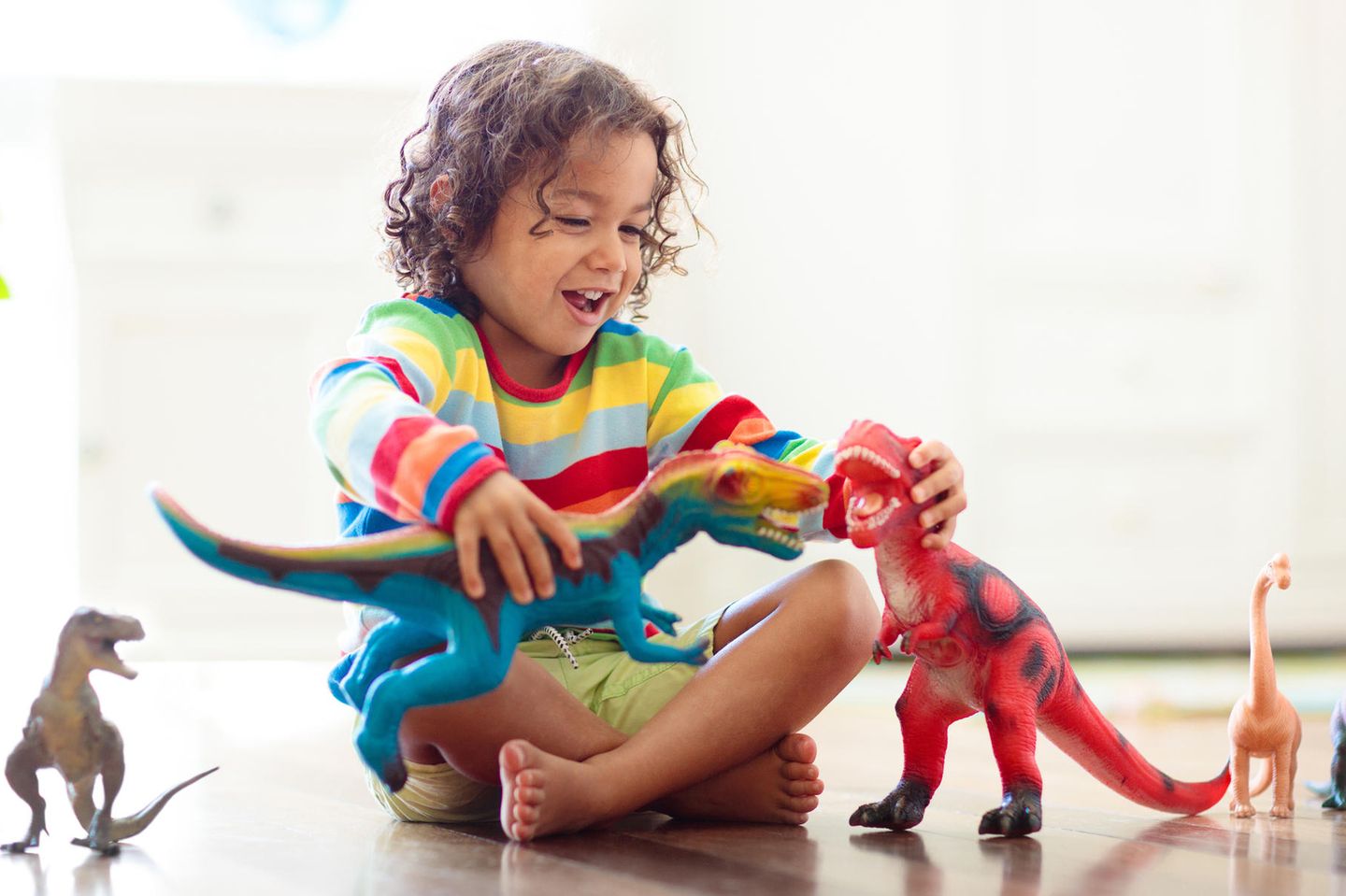 Kind spielt mit Dinosaurier-Spielfiguren