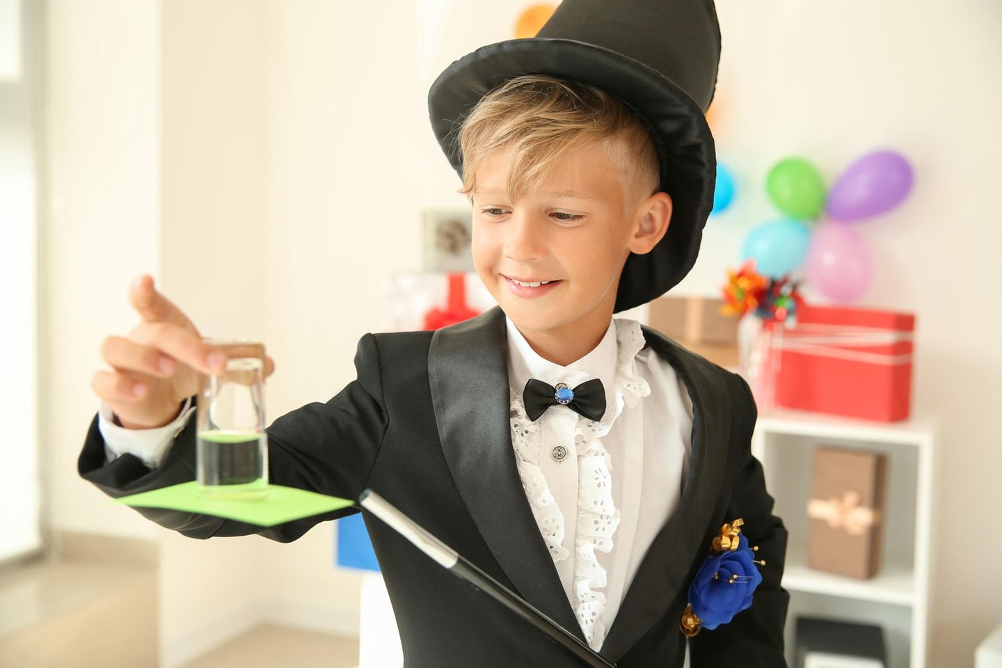 Zaubertricks für Kinder: Junge mit Zylinder und Zauberstab führt einen Zaubertrick vor