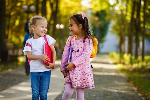 Zwei Mädchen gehen mit Schulranzen zur Schule