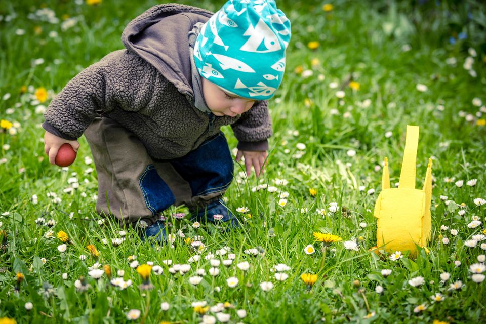 Ein kleiner Junge sucht zu Ostern im Gras nach Süßigkeiten
