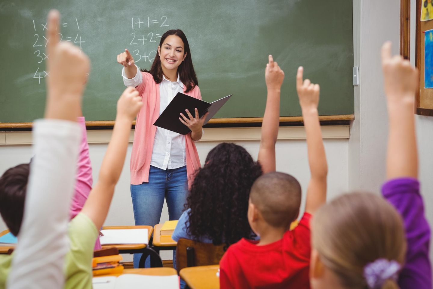 Lehrersprüche: Lehrerin steht vor der Klasse an der Tafel