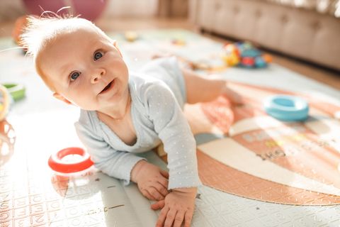 Allergien vorbeugen: Baby auf einem Spielteppich, schaut hoch