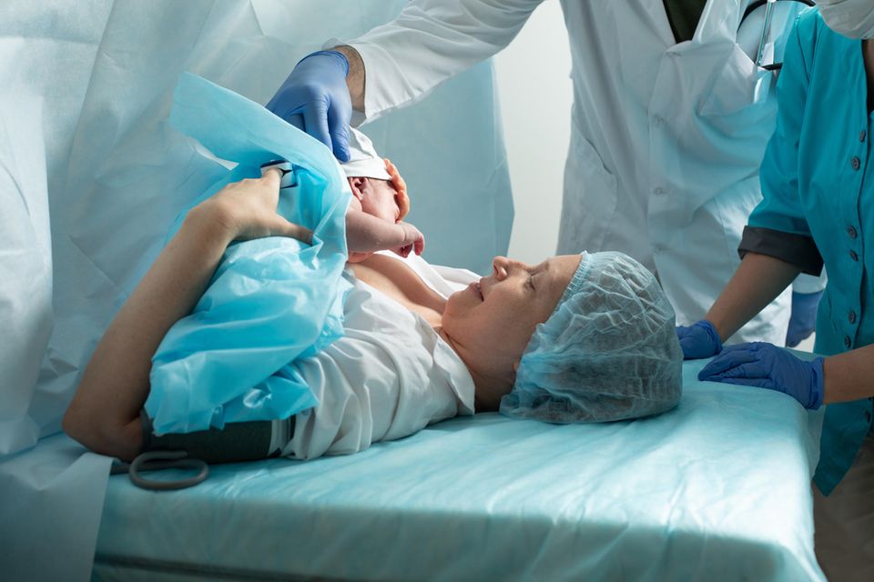 Geplanter Kaiserschnitt: Frau auf OP-Liege bekommt ihr Baby nach einem Kaiserschnitt auf die Brust